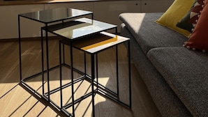 A room with a large window overlooking a body of water, a sofa with cushions, and a small table. - Appartment 2 rooms - Ocean View (Saint-Jean-de-Luz)