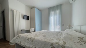 A bedroom with a bed, a desk, a chair, a TV, and a window with curtains. - Holiday Rooms La Campagnetta (Alassio)