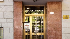 A building entrance with a tiled facade, a numbered plaque, and a sign indicating public access.