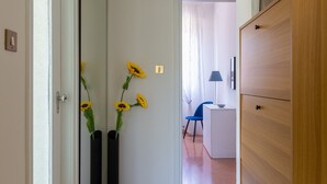 A hallway with a tiled floor, a wooden dresser, and two black vases with yellow flowers.
