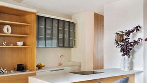 A modern kitchen with a central island, wooden cabinets, and bar stools. - New-Beautiful Rooftop Apartment (Madrid)