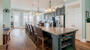 Une cuisine spacieuse dotée d’un grand îlot central, d’appareils électroménagers modernes et de luminaires suspendus.