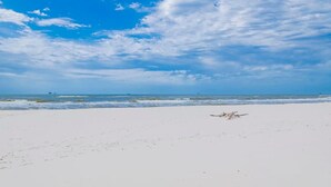 Une plage avec un ciel dégagé et une mer calme.