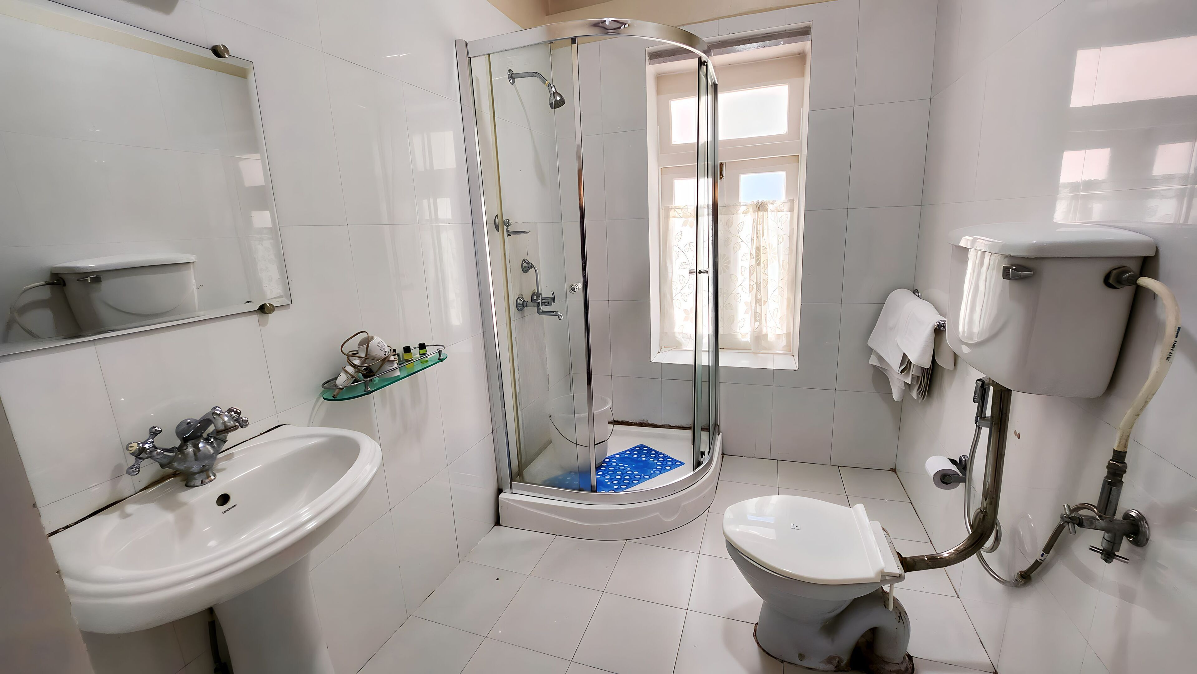 A bathroom with a glass-enclosed shower, a white sink, a toilet, and a mirror.