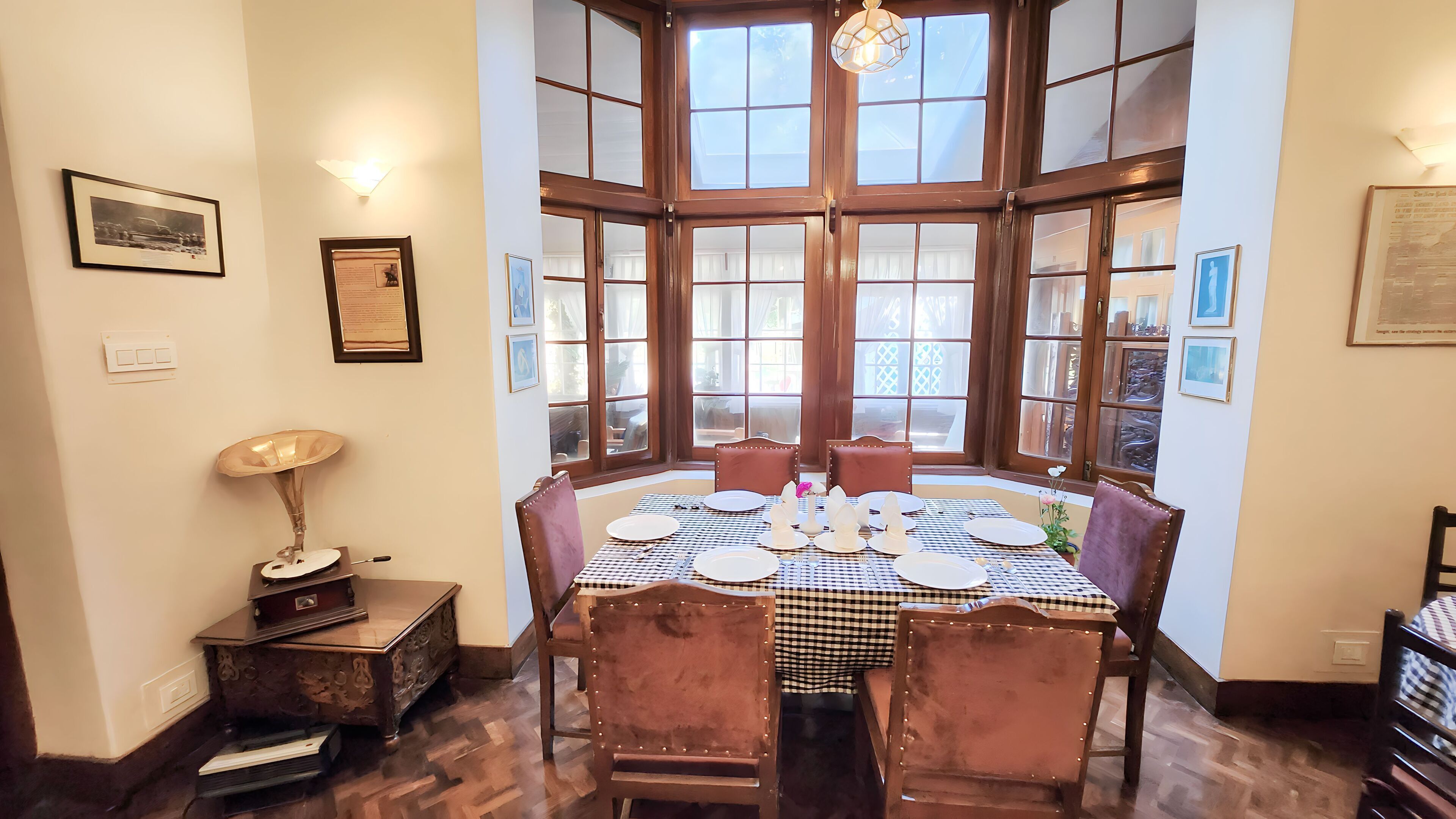 Comedor con mantel a cuadros, sillas de madera y vistas amplias a través de grandes ventanales.