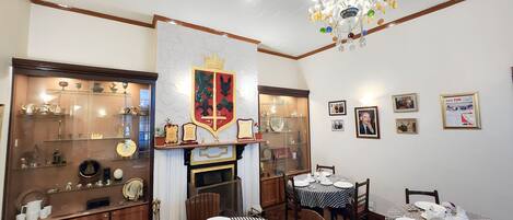 A dining area with checkered tablecloths, a chandelier, and a display of trophies and awards.