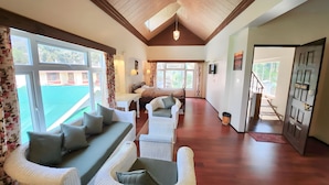 Una habitación amplia con techo alto, vigas de madera, una cama grande, un sofá y un comedor.