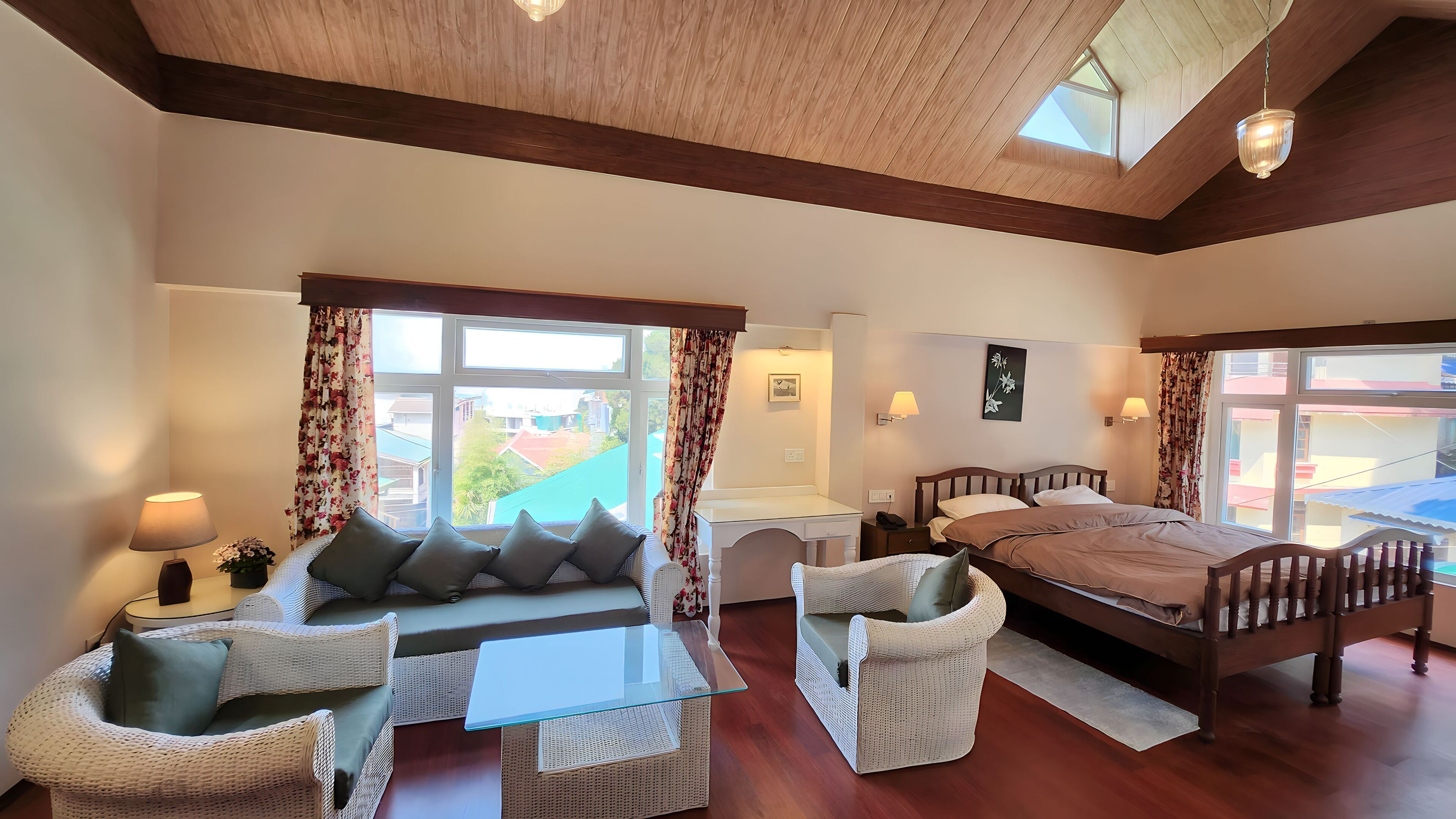 Un dormitorio con cama, sofá, una mesita y ventana con cortinas.
