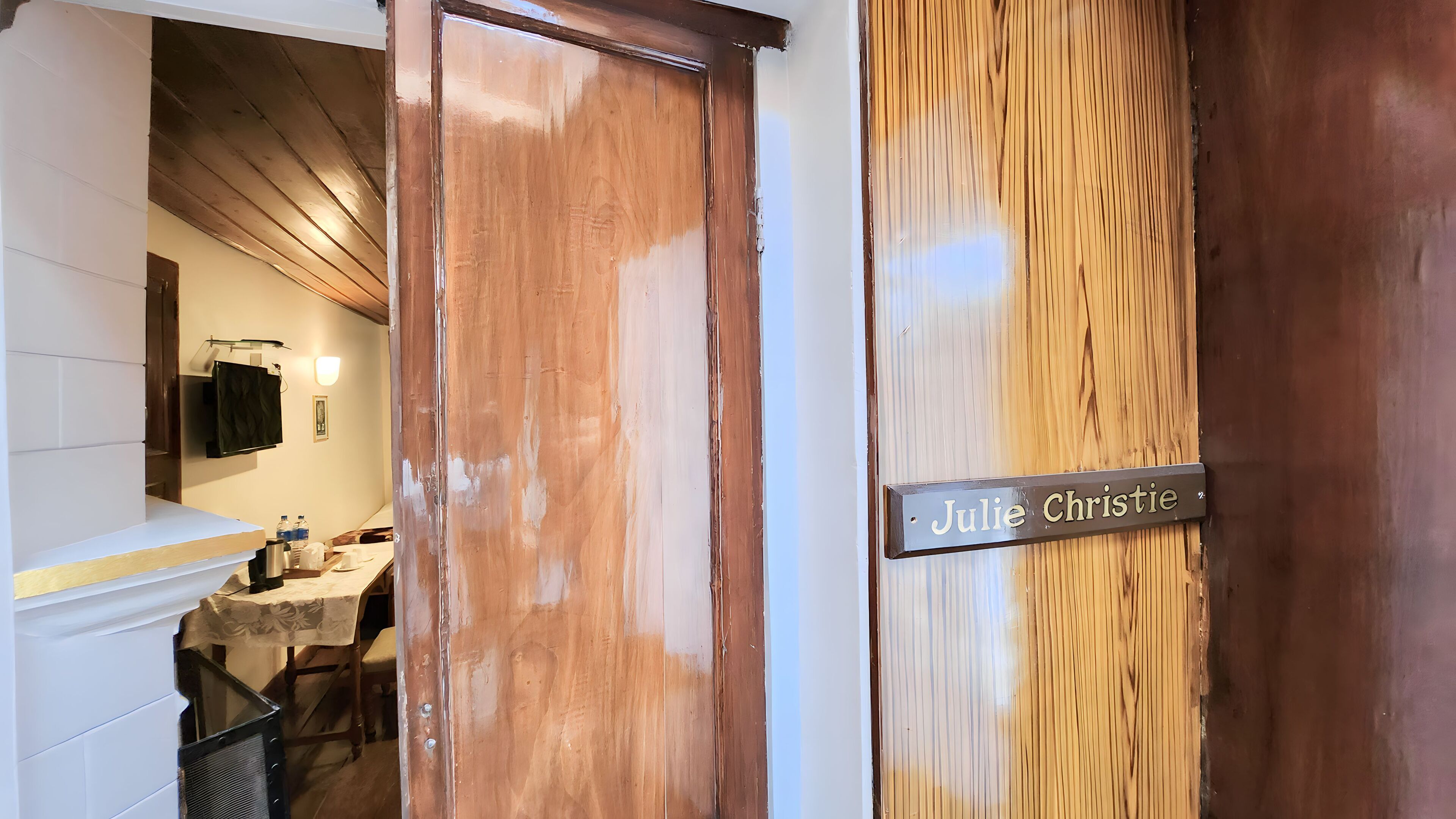 A wooden door with a nameplate reading "Julie Christie" and a glimpse of a room with a table and chairs.