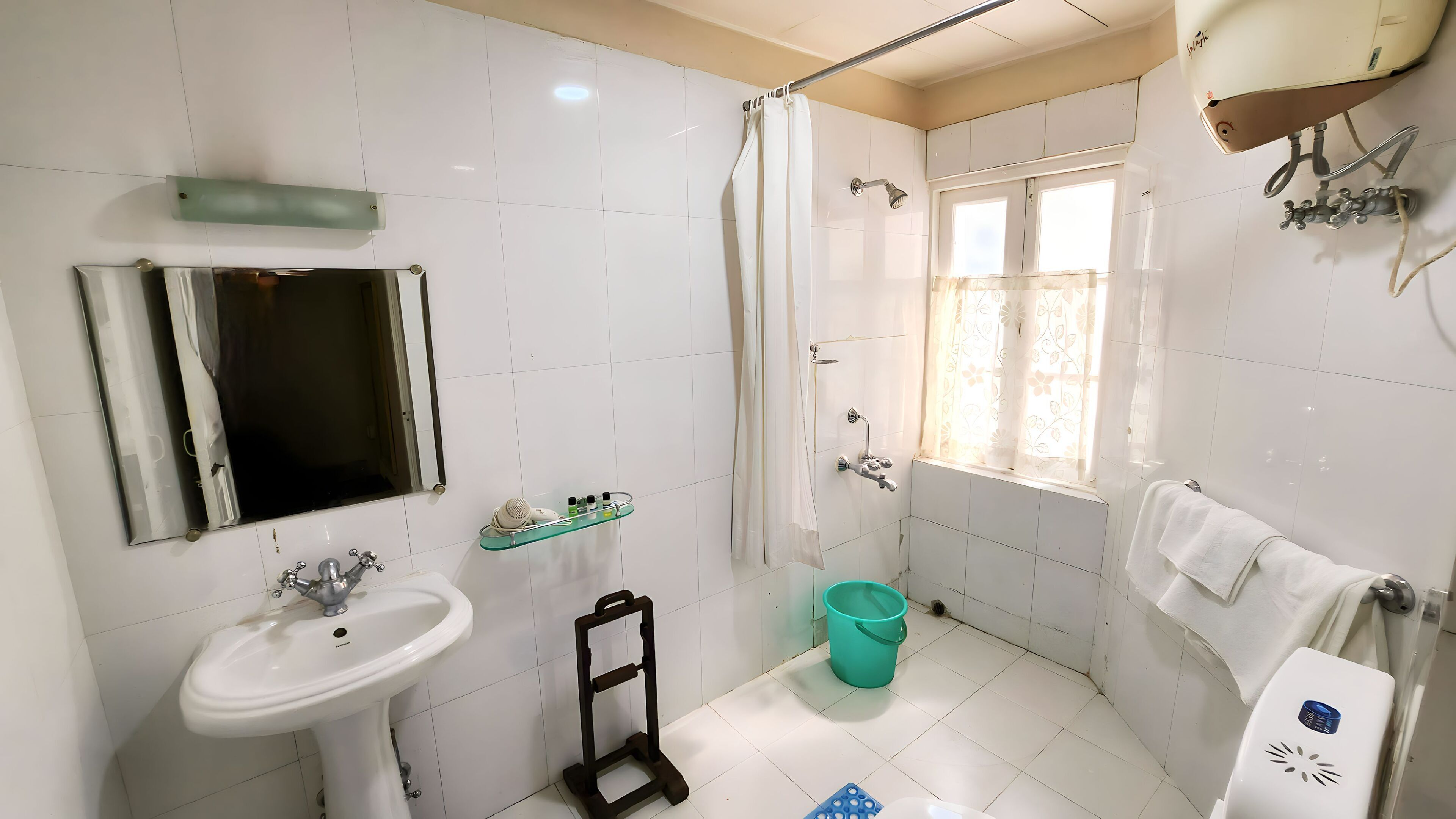 A bathroom with a sink, mirror, shower, and window.