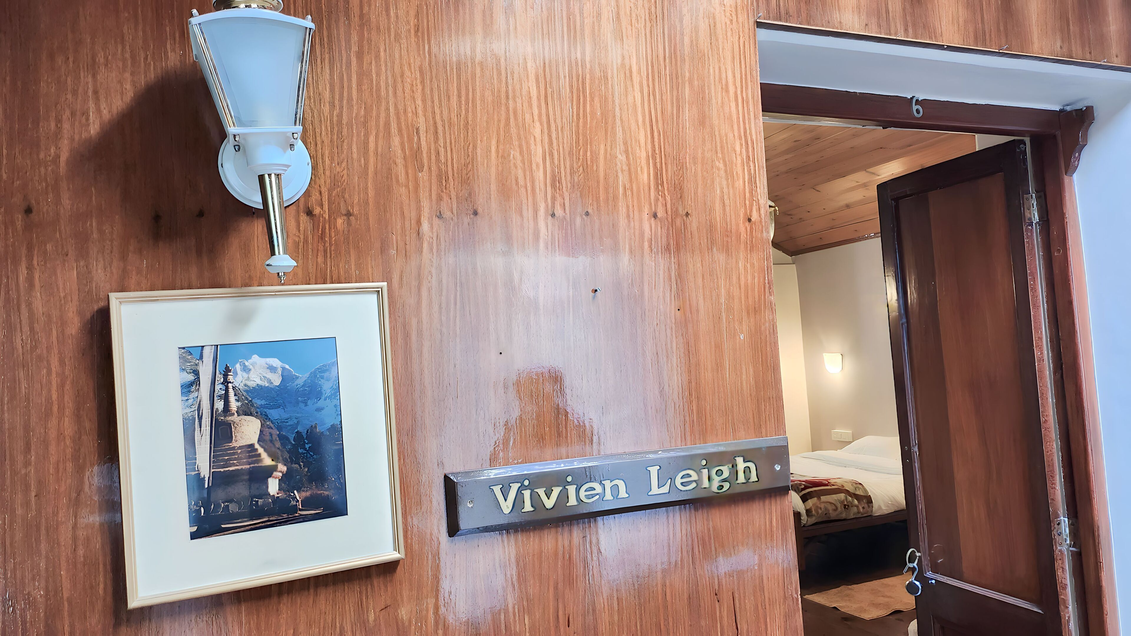 A wooden door with a nameplate reading "Vivien Leigh" and a framed picture of a mountain scene.