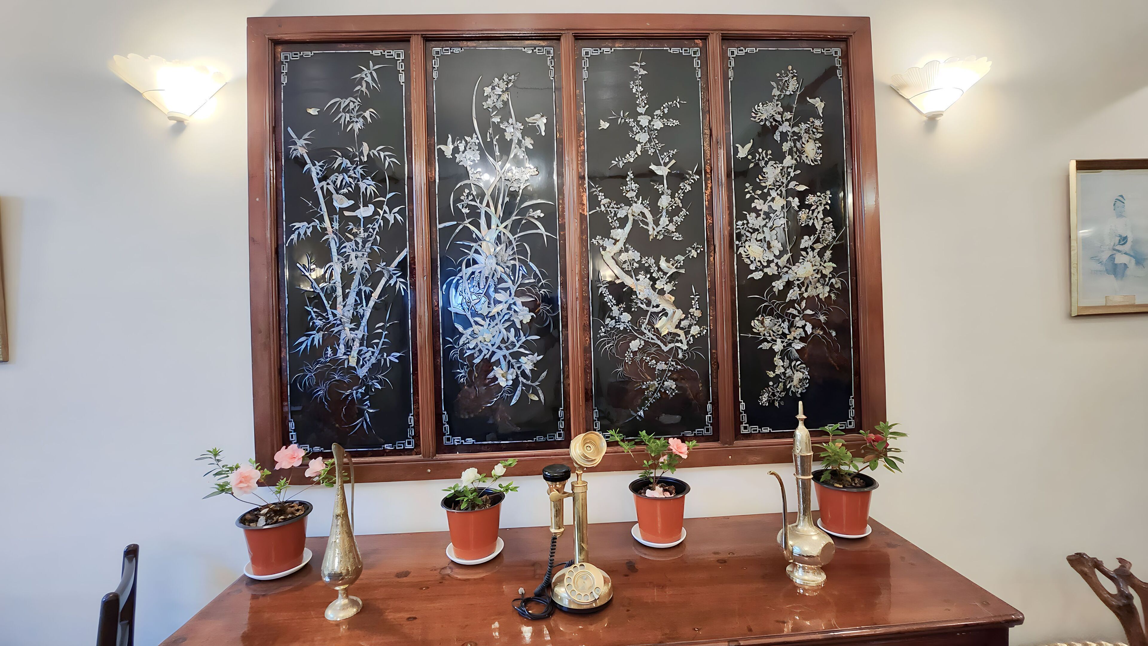 A wooden table with potted plants and a decorative telephone.