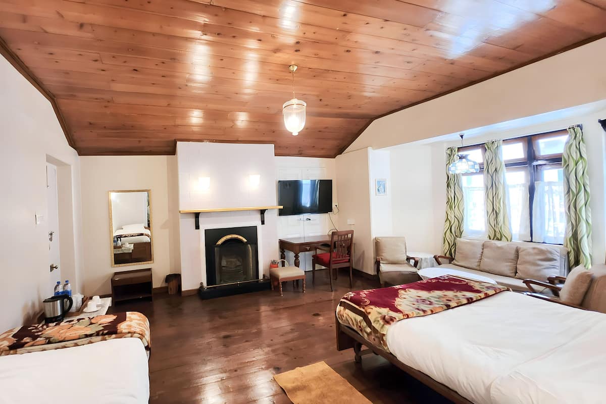 Um quarto amplo com teto de madeira, lareira, televisão, sofá e cama.