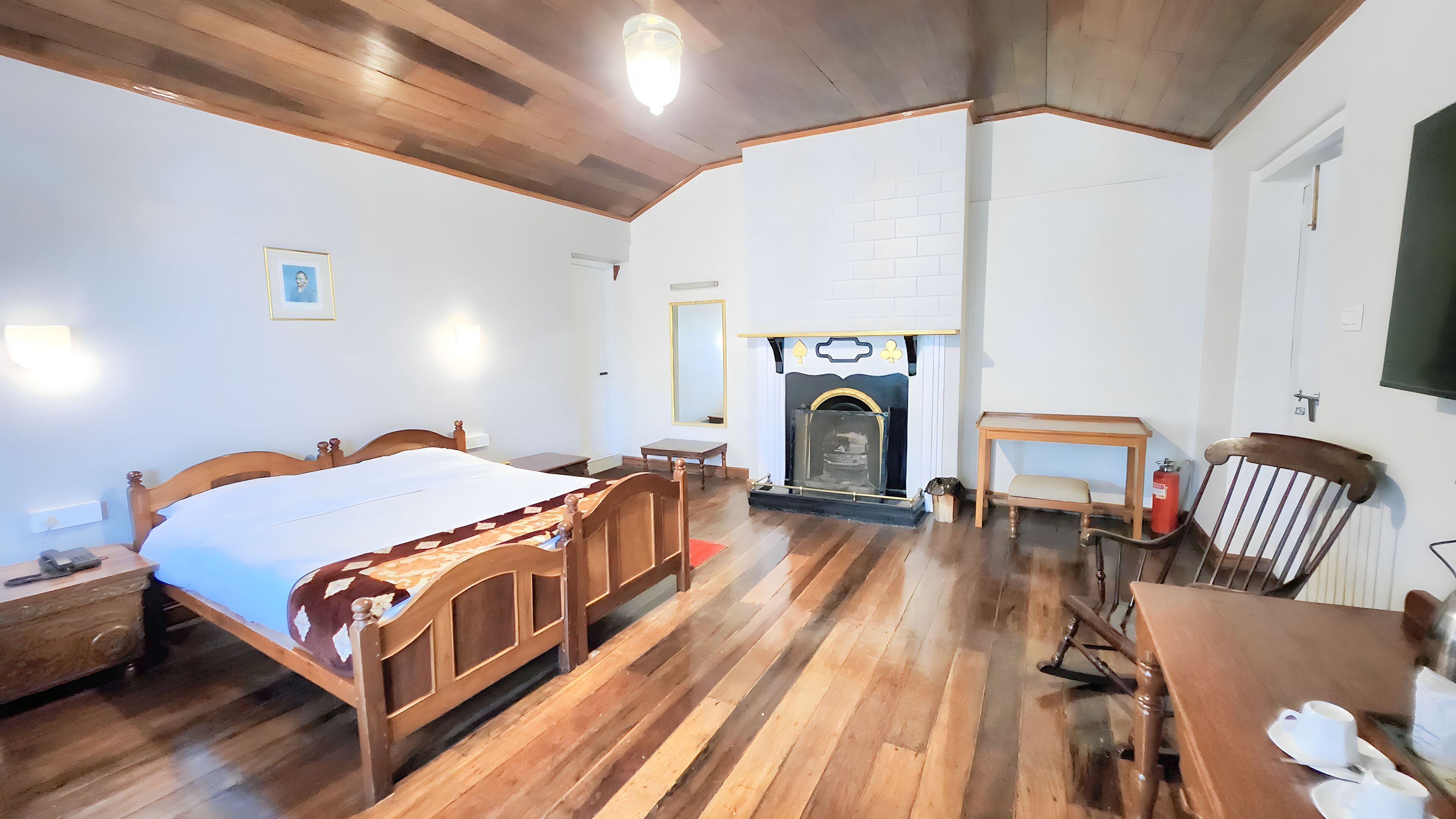 Ein Zimmer mit einem hölzernen Bett, einem Kamin, einem Holztisch und einem Stuhl.