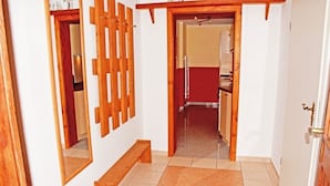 A hallway with a wooden bench, a mirror, and a door leading to a kitchen area. - 1 Bedroom Apartment in Sellin (Sellin)