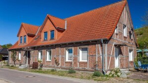 A two-story house with a red-tiled roof, brick walls, and multiple windows. - 1 Bedroom Apartment in Sellin (Sellin)