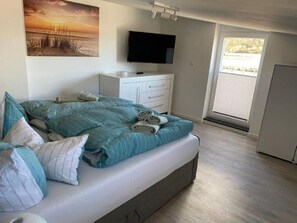 Une chambre à coucher avec un lit, une télévision, une commode et une fenêtre.