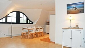 A modern room with a dining area, a white cabinet, and a painting on the wall. - Ferienwohnung 6 Jasmund (Sellin)