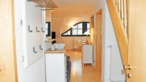 A narrow hallway with a wooden staircase on the right, leading to a room with a window and a radiator. - Ferienwohnung 6 Jasmund (Sellin)