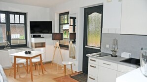 Una cocina moderna con armarios blancos, un comedor con mesa y sillas blancas, y un ventanal que proporciona luz natural.
