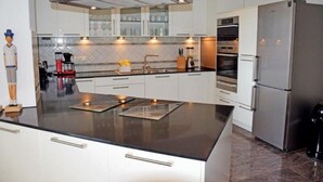 Cozinha moderna com ilha central, eletrodomésticos de aço inoxidável e armários brancos.