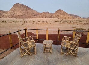A terrace with wicker furniture overlooking a desert landscape with mountains. - Adel rum camp  (Wadi Rum)