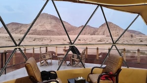 A desert view from a vehicle with a covered seating area, including chairs and a table. - Adel rum camp  (Wadi Rum)
