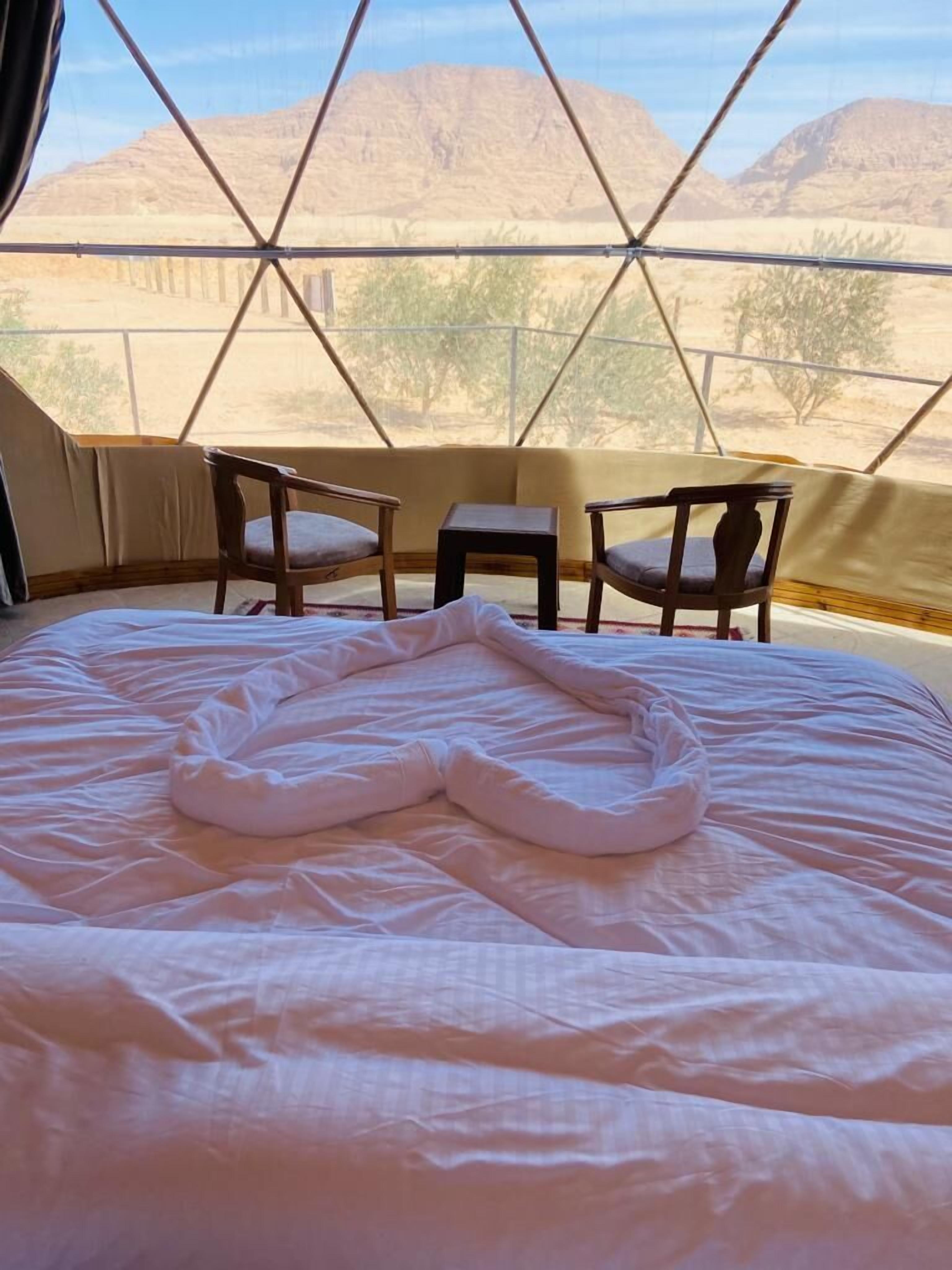 A tent with a bed, two chairs, and a small table.