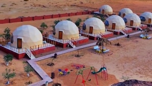 A desert landscape with several dome-shaped structures, likely accommodations, connected by pathways. - Adel rum camp  (Wadi Rum)