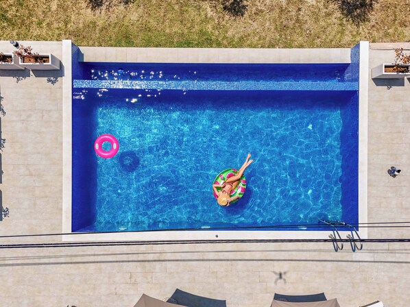 Une piscine rectangulaire à l’eau d’un bleu limpide, entourée d’une terrasse carrelée.