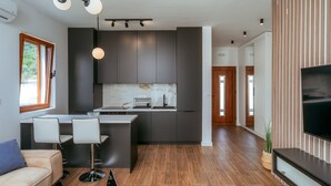 A modern kitchen with dark cabinetry, a central island, and pendant lighting. - Uphill Glavanovic Pool Villa (Bar)