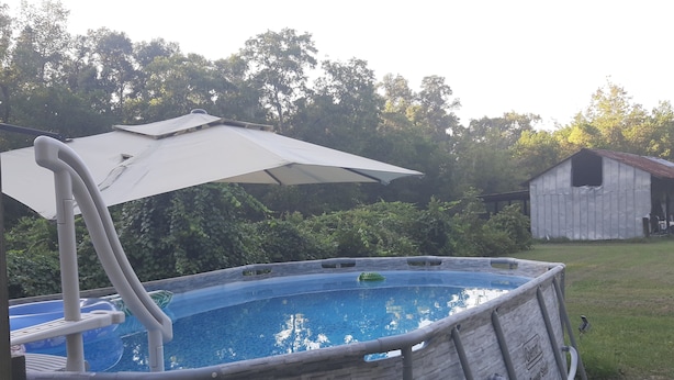 An above-ground swimming pool with a ladder and an umbrella. - Private, 1 Mile to Poe, 4 miles to Blue, 6 Miles to Ginnie. Tent/Camper camping (High Springs)