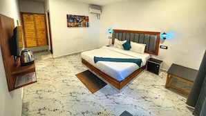 A hotel room with a bed, a ceiling fan, a painting, and a wooden wardrobe. - White Truffle Resort (Arambol)