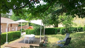 Un'area patio con tavolo e sedie, una zona relax coperta e un prato.