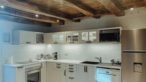 Una cucina moderna con mobili bianchi, elettrodomestici in acciaio inossidabile e soffitto in legno.