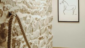 Un muro in pietra con una corda, un quadro incorniciato e un soffitto con travi in legno.