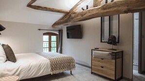 Una camera da letto con un letto, un comodino, una lampada, una televisione e una finestra con persiane.