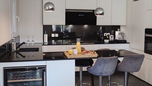 A modern kitchen with white cabinets, a black countertop, and two bar stools.