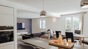 A modern kitchen with a dining area, a sofa, and a TV.