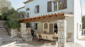 A stone patio with a pergola, outdoor dining set, and a stone staircase.