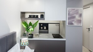 A compact kitchen with a built-in coffee machine, a sink, and a countertop.