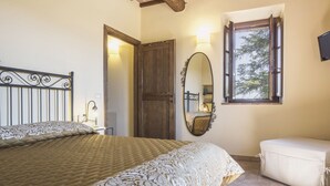 Een slaapkamer met een bed, een houten deur, een raam, een spiegel en een nachtkastje.