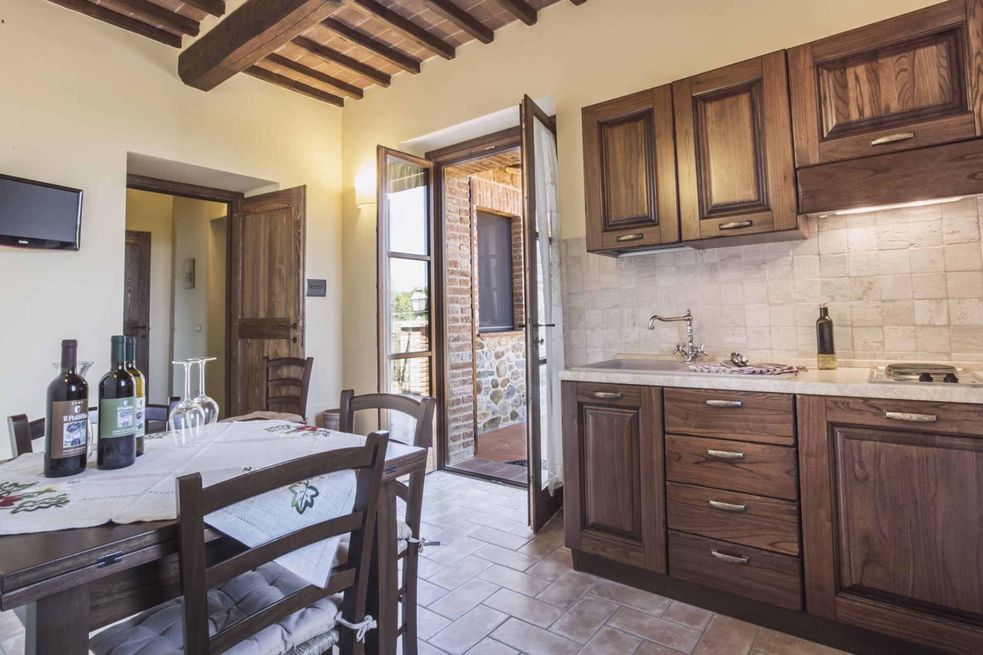 A kitchen with wooden cabinets, a tiled backsplash, and a dining area with a table set for two.