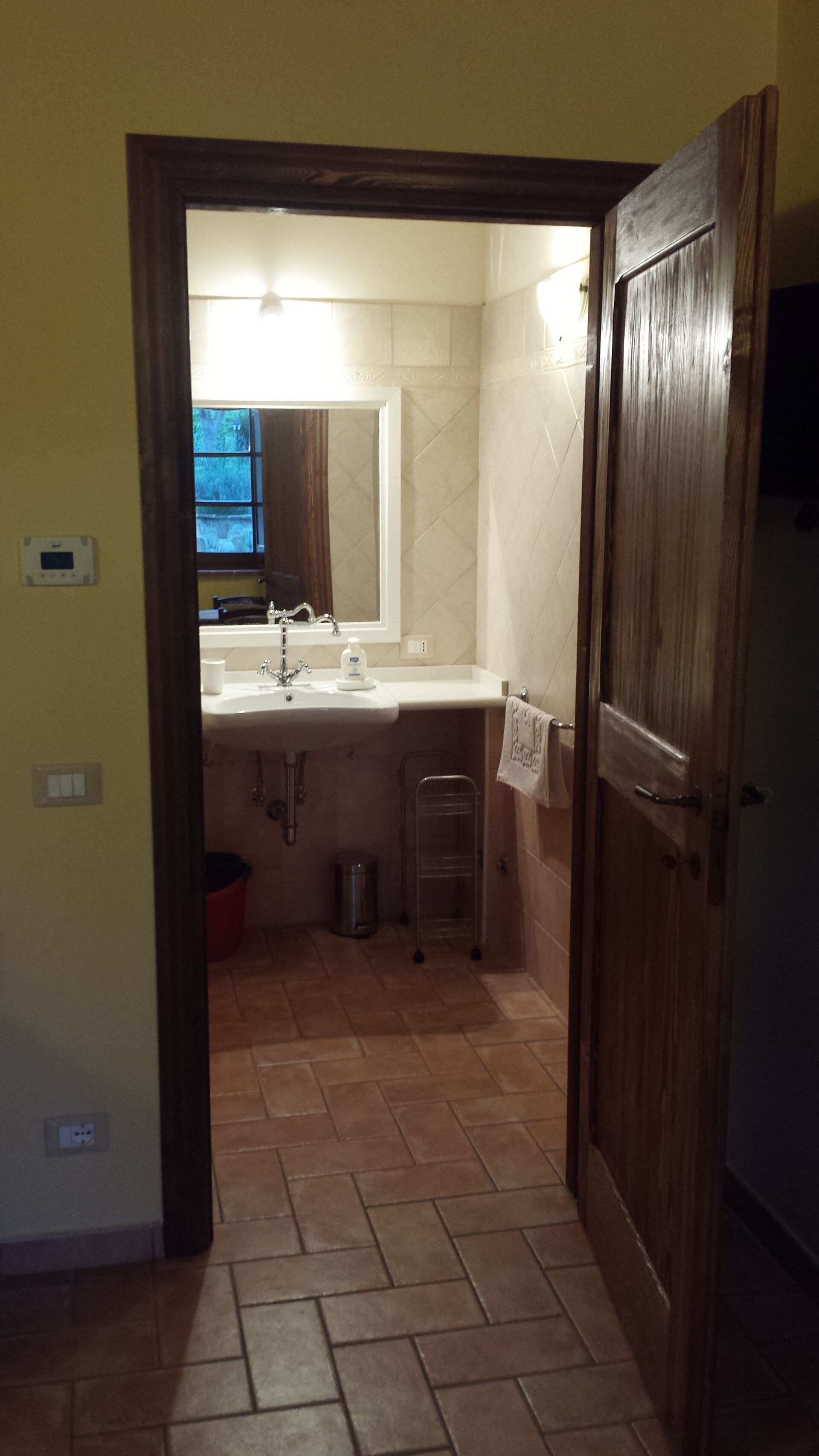 Baño con lavabo, espejo y perchero para toallas.
