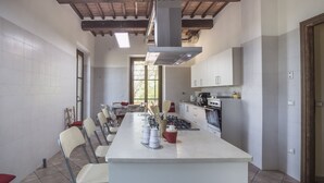 Une cuisine moderne dotée d’un îlot central, de meubles blancs et d’une grande fenêtre qui laisse entrer la lumière naturelle.