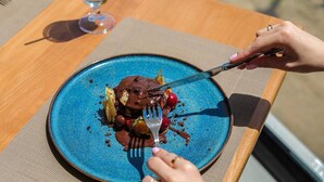A blue plate with a dessert on a wooden table. - Black Diamond Hotel Dhermi (Himarë)