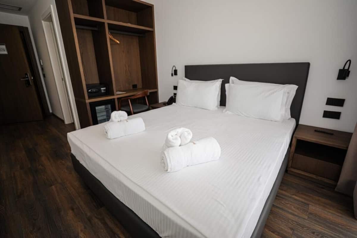 Une chambre d’hôtel avec un grand lit, une armoire en bois et un bureau avec une chaise.