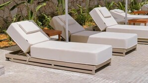A rooftop lounge area with white lounge chairs and umbrellas, a stone wall, and a view of the building's interior. - Black Diamond Hotel Dhermi (Himarë)