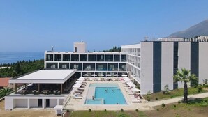 A modern hotel with a pool area, outdoor seating, and a view of the sea. - Black Diamond Hotel Dhermi (Himarë)
