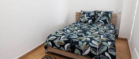 Ein Schlafzimmer mit Bett, einem gemusterten Teppich und einer Hängelampe.